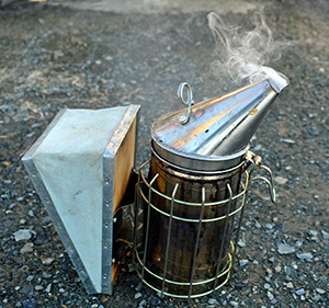 a bee smoker with cool white smoke coming from the spout